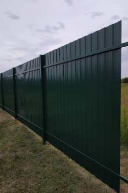 Tornavidayla çalışan işçi vidaları çitlere vidalıyor ve metal bir çit takıyor.