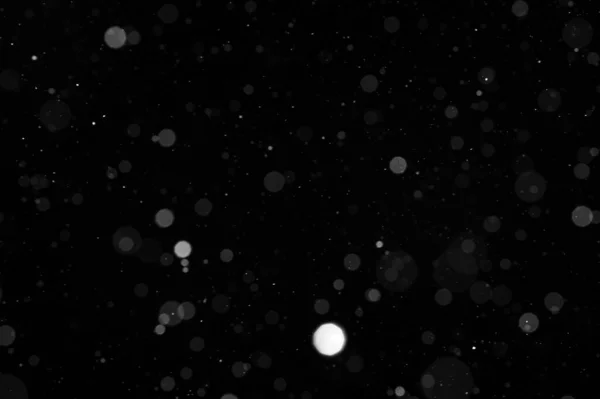 Bokeh of white snow on a black background. Snowfall - new design element.