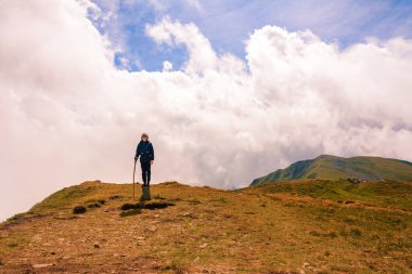 Dağın tepesindeki bir turist kollarını bir kuş gibi açtı, dağların yüksekliğinin ve ihtişamının tadını çıkarıyordu. 2020