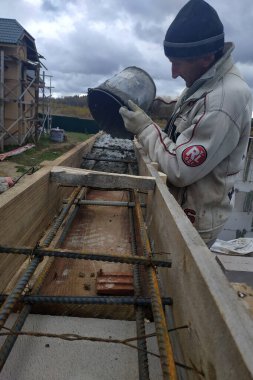 Kaluga, Rusya 13 Ekim 2019: İnşaat işi, bir işçi bir kovadan formaliteye beton döküyor. yeni