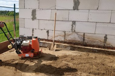 Titreşimli levha kullanılıyor, titreşimli levha yardımıyla kumu sıkıştırıyor, yeni bir ev inşa ediyor.