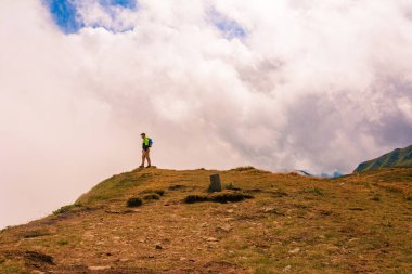Dağın tepesindeki bir turist kollarını bir kuş gibi açtı, dağların yüksekliğinin ve ihtişamının tadını çıkarıyordu. 2020