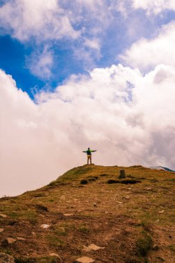 Dağın tepesindeki bir turist kollarını bir kuş gibi açtı, dağların yüksekliğinin ve ihtişamının tadını çıkarıyordu. 2020