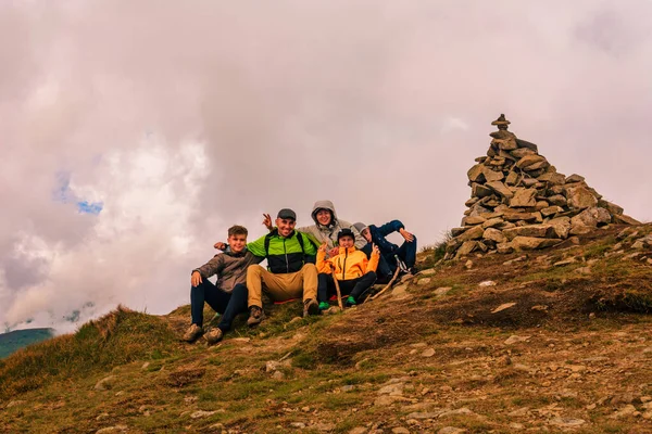 A group of tourists are sitting smiling on top of the mountains of the Montenegrin ridge, Mount Rebra is one of the peaks of the Carpathian mountains.2020