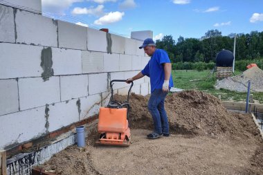 İnşaat alanında inşaat işi, titreşim plakalı toprak sıkıştırma, elle kumanda. Yeni.