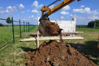 Sarı kazıcı çukur kazıyor, inşaat otomobil teçhizatı vasıtasıyla yapılıyor. Yeni