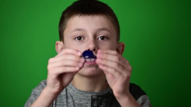 녹색 배경에 있는 소년은 앞니의 정렬을 위한 판위에 윗 치아의 정렬을 위한 판을 놓는다. — 비디오