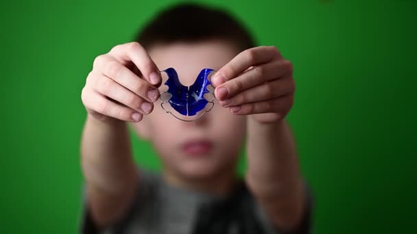 Мальчик на зеленом фоне кладет на тарелку для выравнивания передних верхних зубов, выравнивания верхних зубов. — стоковое видео