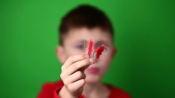 Un bambino di 9 anni tiene una piastra di allineamento dentale, un abominio e una dimostrazione di una piastra di allineamento dentale. — Video Stock