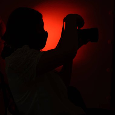 Kırmızı arka planda siluetli bir adam, ünlüleri izliyor, fotoğrafçı avlanıyor..