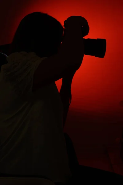 Man in silhouette on a red background, watching celebrities, photographer on the hunt.