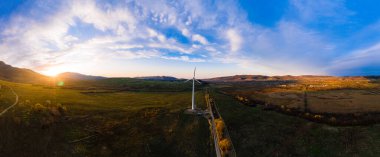 Kırsal yoldan rüzgar türbinine kadar uzanan panoramik manzara, Ukrayna 'da rüzgar enerjisinin gelişimi. yeni