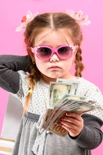 ピンクの背景 子供やショッピングにパッケージとお金を眼鏡で女の子 新しい — ストック写真
