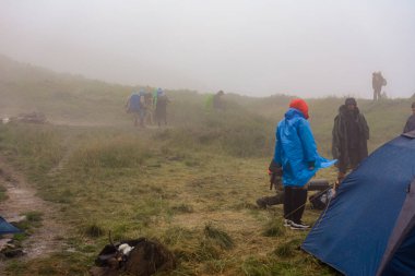 Karpatlar, Ukrayna 24 Ağustos 2020: Dağda göl, dağlarda yağmur, yağmurluk içinde turistler, Karpatlar 'daki göl kenarında sis, Ukrayna' nın en yüksek gölü Brebeneskul 'da. yeni