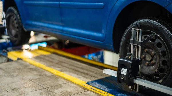 Primer plano de un neumático sujetado por un nivelador que pasa la alineación automática de las ruedas en el garaje, garaje y herramientas para el mecánico. —  Fotos de Stock