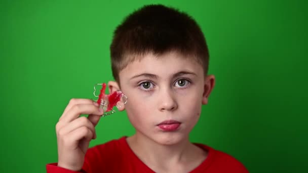 Um menino de 9 anos está segurando uma placa de alinhamento dentário, uma abominação e uma demonstração de uma placa de alinhamento dentário. — Vídeo de Stock