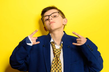 Sarı arka planda yetişkin kıyafetli çekici bir çocuk, bir çocuğun yetişkin hayatı hakkındaki hayal gücü. yeni