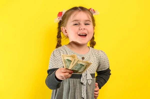 幸せな子供のお金を保持 お金の多くで子供たちの喜び 黄色の背景に女の子の肖像画 新しい — ストック写真