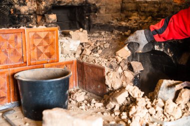 Eski bir tuğla soba, kurum içinde tuğla, eski mutfağı elleriyle söküyor, usta elleriyle tuğladan yuvarlanıyor. yeni