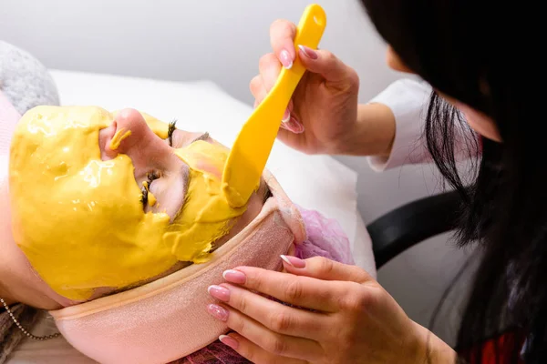 Mulher Esteticista Aplicando Uma Máscara Dourada Relaxante Rosto Restaurando Hidratando — Fotografia de Stock