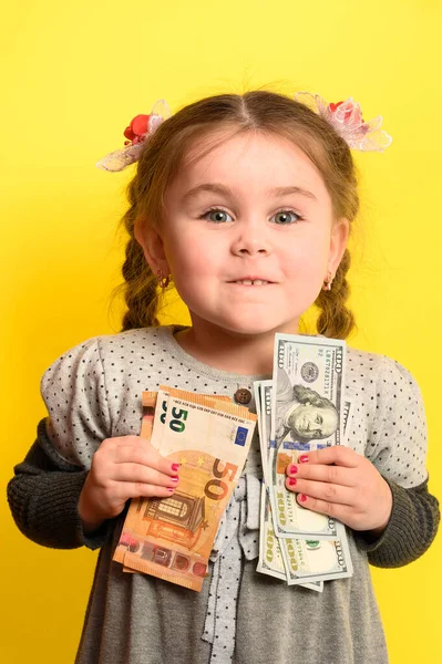 黄色の背景に手に銀行券を持つ少女は 世界通貨とビジネスの子供 新しい — ストック写真