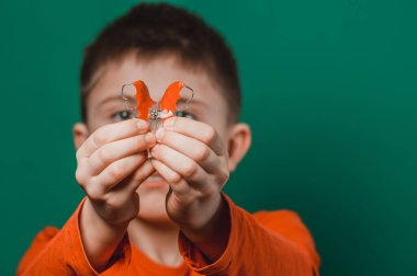 Yeşil arka planda bir çocuk dişlerini hizalamak için plakasını gösteriyor. yeni