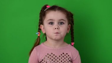 Yeşil arka plandaki kız bir öpücük, bir çocuk öpücüğü gösteriyor..