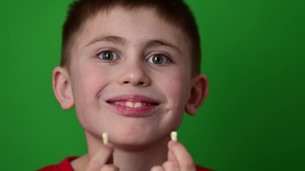 Jongen in zijn handen houdt zijn baby twee tanden, baby op een groene achtergrond. — Stockvideo