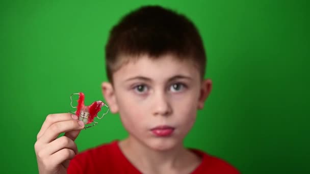 Un niño de 9 años sostiene una placa de alineación dental, una abominación y una demostración de una placa de alineación dental. — Vídeo de stock