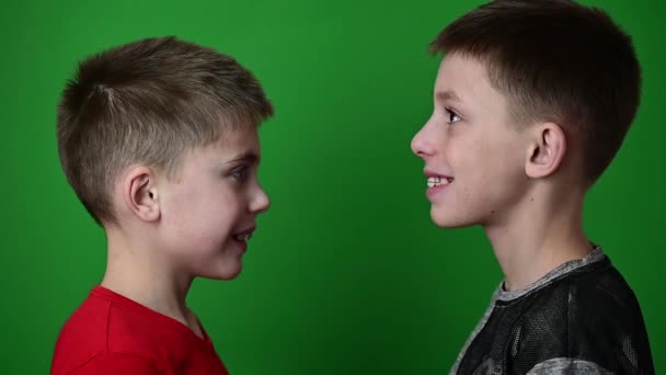 Zwei Jungen tragen Zahnbeläge, Kinder auf grünem Hintergrund stehen im Profil. — Stockvideo