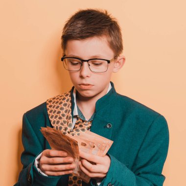 Yetişkin ve büyük beden takım elbiseli 11 yaşındaki bir çocuğun elinde bir avro, sarı arka planda parası olan bir çocuğun portresi var. yeni