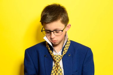 Sarı arka planda, üzgün bir ifadeyle bir çocuğun portresi, bir çocuğun üzerinde yetişkin kostümü. yeni