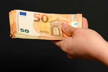 Siyah arka plandaki bir adamın elinde avroya para transferi ve iş ödülü olarak para almak. yeni