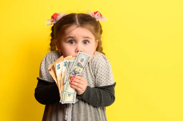 黄色の背景に手に銀行券を持つ少女は 世界通貨とビジネスの子供 新しい — ストック写真