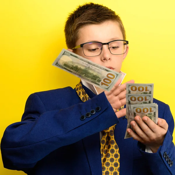 The guy in an adult suit waves American dollars, a portrait of a child on a yellow background. new