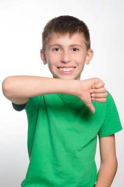 Yeşil tişörtlü genç adam baş parmağını kaldırıyor. Yüz ifadesi onay ya da sevinç gösteriyor. Düz beyaz arkaplan.