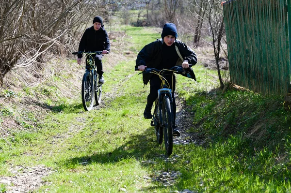 Kırsal kesimde bisiklet süren aktif gençler. Parlak güneş ışığı gölgeler oluşturur. Barışçıl bir açık hava macerası.