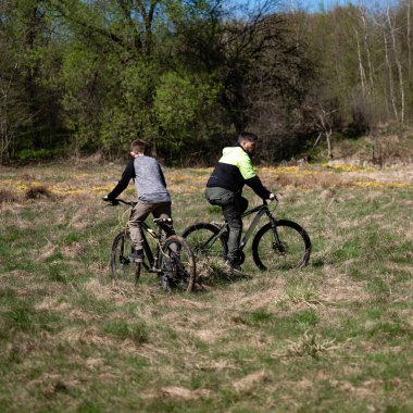 Baba ve oğul tarlada bisiklet sürüyor. Doğada aileyle aktif eğlence..