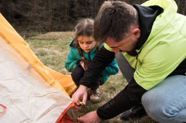 Bir baba genç kızına kamp gezileri sırasında nasıl çadır kurulacağını gösterir. Sıcak güneş ışığı ve yemyeşil ortamda güzel anılar yaratır..
