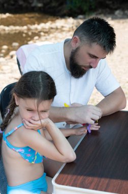 Sakallı bir baba sakin bir derenin yakınındaki bir sanat projesinde kızına yardım ediyor. Odaklanıyorlar ve birlikte iyi vakit geçiriyorlar..
