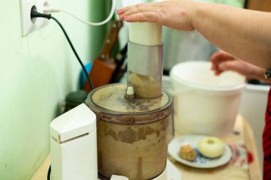 Eller sıcak bir mutfakta yemek işlemcisini ustalıkla çalıştırır. Lezzetli bir karışım için malzemeleri karıştırır..