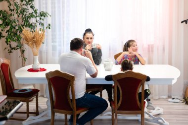 Aile üyeleri geniş bir yemek masasının etrafında toplanmış, rahatlatıcı içecekler yudumluyor ve perdelerin arasından gün ışığı akarken hoş sohbetlere dalıyorlardı..