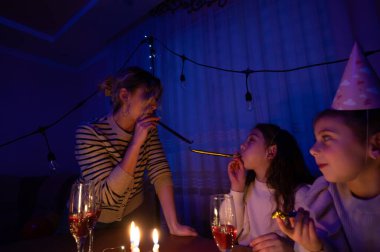 Kahkahalar loş bir odayı dolduruyor. Aile üyeleri özel bir olayı kutlarken bir masaya toplanıp köpüklü içkilerle süsleniyorlar, neşeli parti kornalarının keyfini çıkarıyorlar..