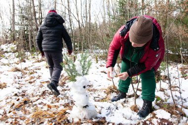 İki kişi ormanlık alanda küçük bir kardan adam yapar. Bir kişi figüre kar eklerken, diğeri yürüyüp gidiyor. Sahne huzurlu ve karlı, kış aktivitelerini gözler önüne seriyor.