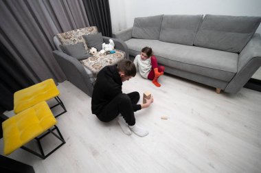 İki çocuk, rahat ve sıcak bir oturma odasının zeminine ahşap bloklarla dolu bir kule inşa ederken, eğlenceli bir yaratıcılıkla meşgul oluyorlar..