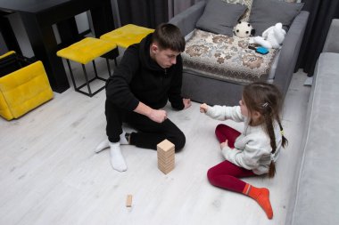 Bir erkek ve bir kız birlikte vakit geçirmenin keyfini çıkarıyorlar, eğlenceli bir kule inşaatı oyunu oynuyorlar. Etkileşim halinde olduklarında ifadeleri heyecan ve konsantrasyon gösteriyor..