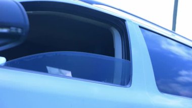 Bir arabanın penceresinden, bulutlarla benekli parlak mavi bir gökyüzünü gösteren sakin bir manzara belirir. Güneş ışığı yaklaşan maceraları ve yolculukları ima ederek filtreler. Arabanın kapısının camını kaldırıyorum..