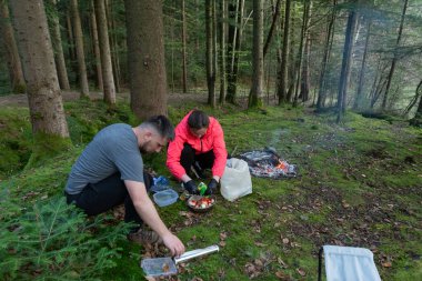 İki birey, yemyeşil bir ormanda, açık bir ateşin üzerinde lezzetli bir yemek hazırlar. Mutfak maceraları boyunca dostluk ve doğa için minnettarlık gösterirler..