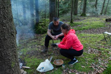 Sessiz bir orman açıklığında, bir çift birlikte yemek pişirirken doğanın huzurunun tadını çıkarırlar. Yumuşak ışık macera ve bağlantılarla dolu rahat bir atmosfer yaratır..