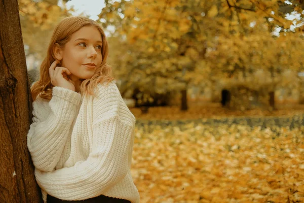 秋の公園の女性 紅葉を背景に10代の少女 白い暖かいセーターのモデルのファッション写真 ブロンドは距離を調べる — ストック写真